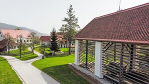 Un sendero conduce a un edificio con tejado de tejas rojas, rodeado de césped verde y árboles.