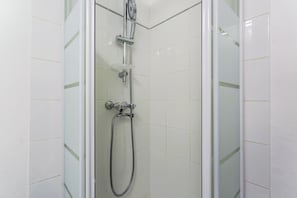 Eine Duschkabine mit einer Handbrause, einem Wandarmaturen-Set und einem flexiblen Schlauch.