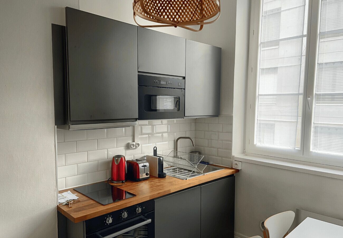 Una cocina moderna con horno empotrado, microondas y encimera de madera.