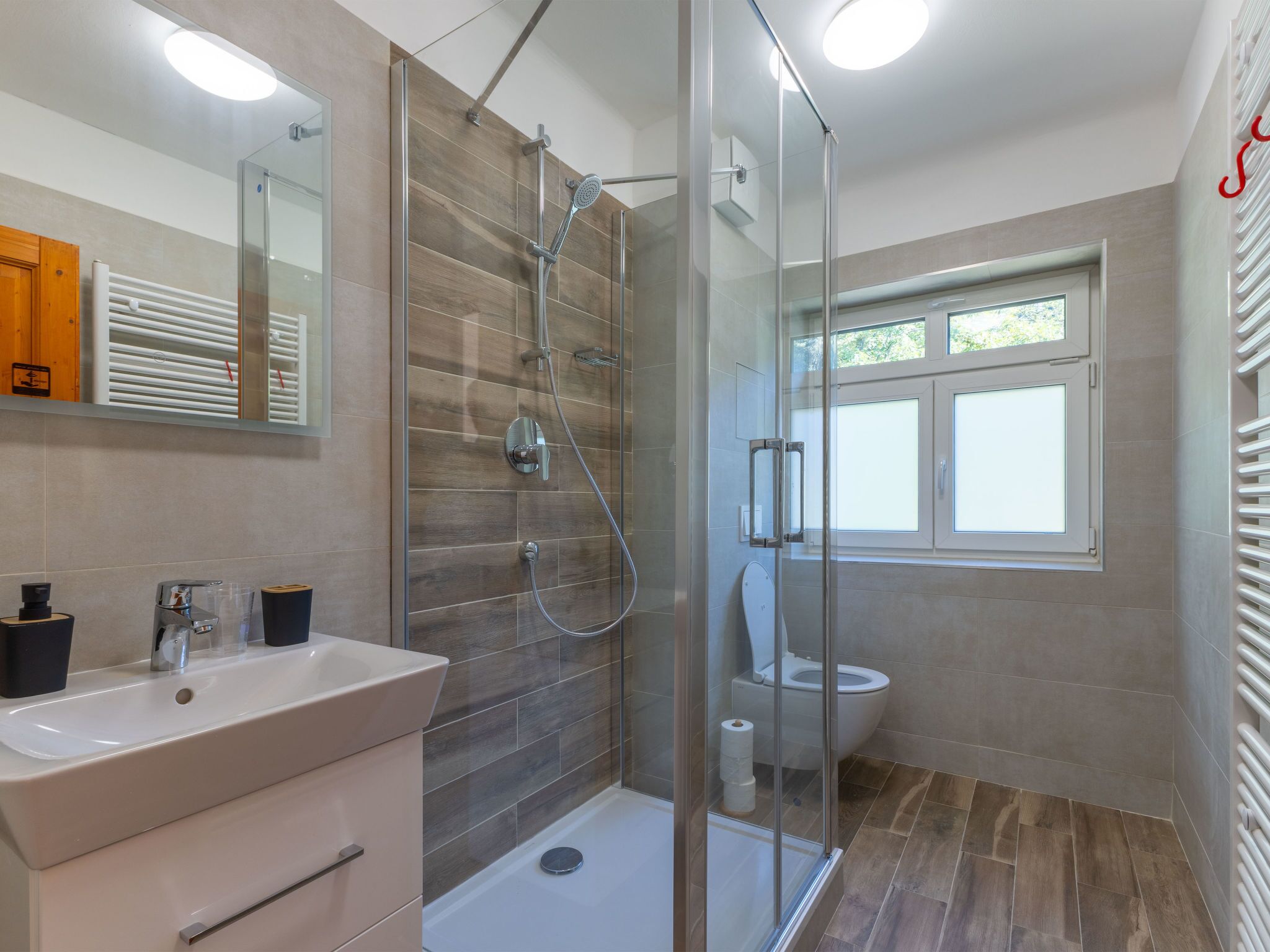 Un baño moderno con cabina de ducha de vidrio, inodoro y lavabo.