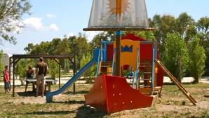 Un parque infantil con un tobogán, estructuras para escalar y una casita con forma de velero.