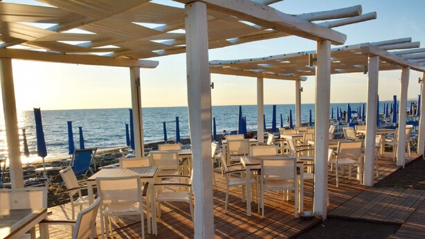 Un café frente al mar con terraza y sombrillas.