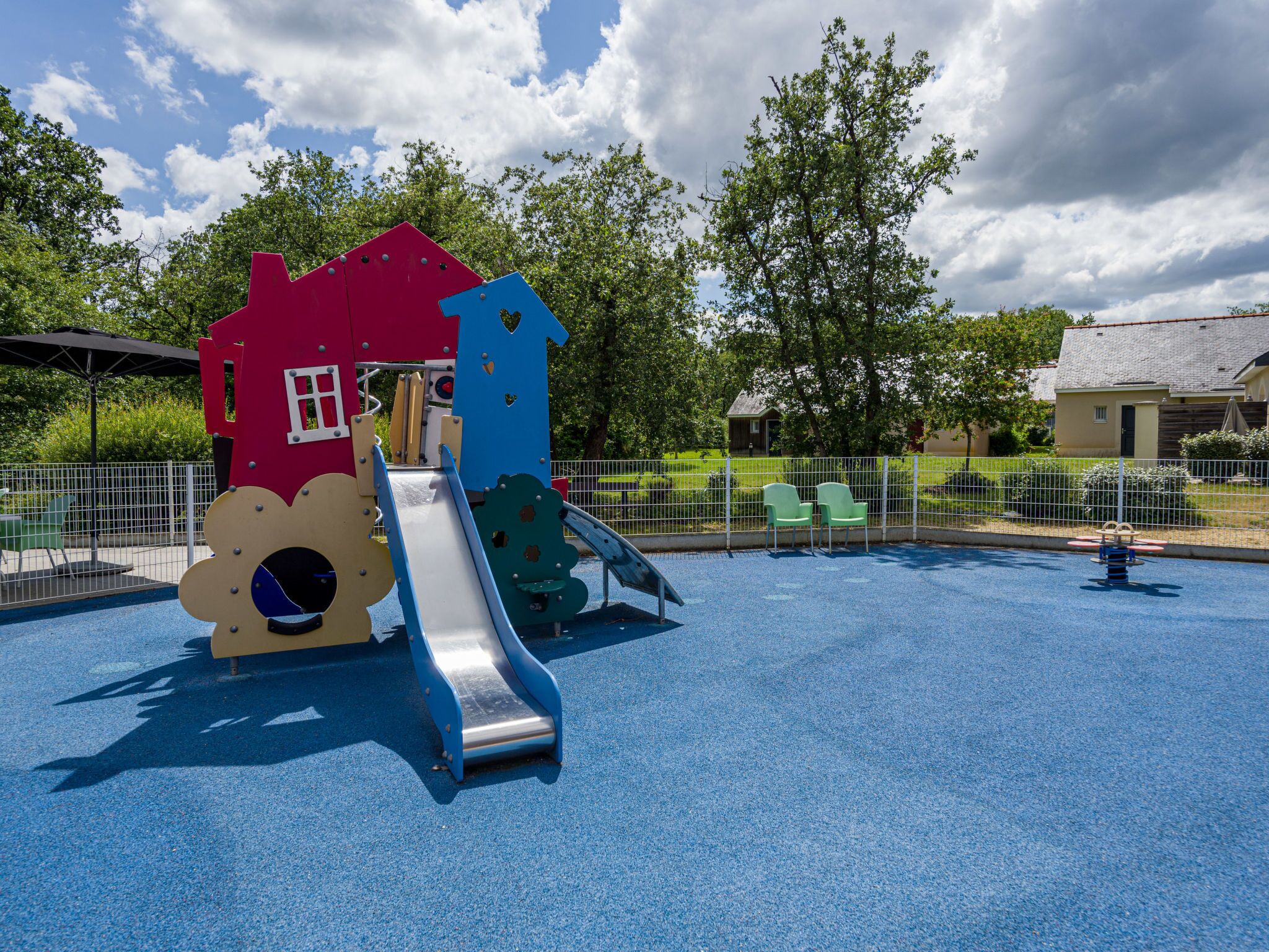 A playground with a slide, climbing structures, and a red house-shaped play area.