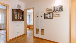 Un pasillo con suelo de madera, un armario de madera y una pared decorada con fotografías enmarcadas.
