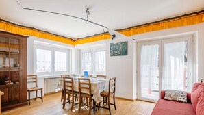 Un comedor con una mesa y sillas de madera, un sofá rojo y un aparador con puertas de cristal.