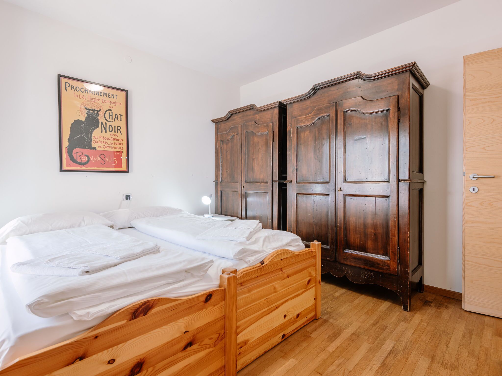A bedroom with a wooden bed, a wardrobe, and a poster on the wall.