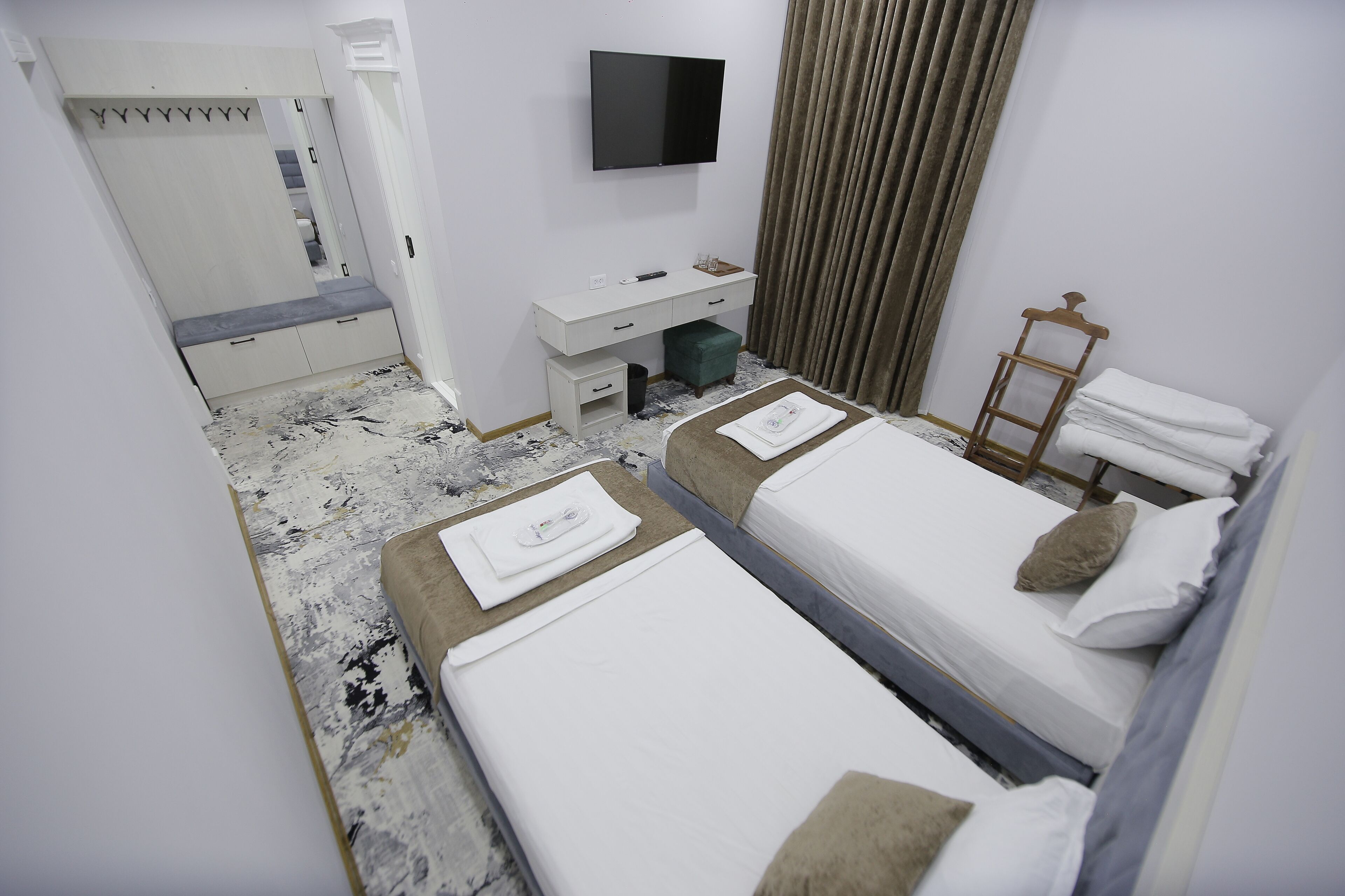 A hotel room with two beds, a desk, a TV, and a wardrobe.