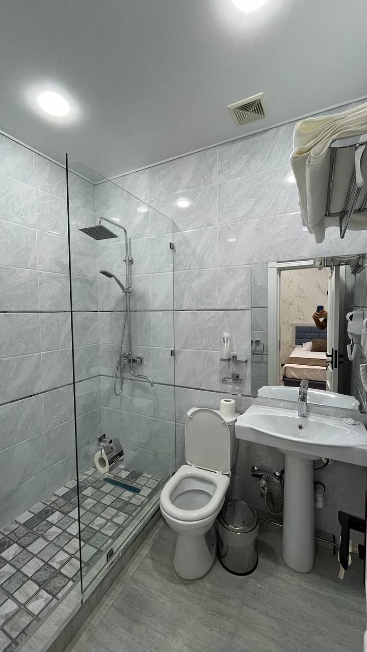 Un baño moderno con ducha acristalada, inodoro y lavabo con espejo.
