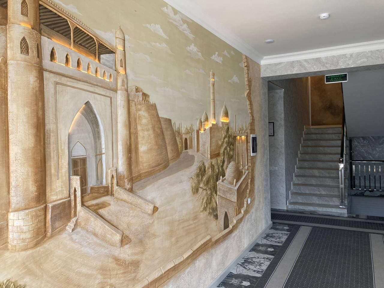 A detailed mural of a castle interior with a staircase leading to a door, a reception desk, and a sign indicating the lobby area.