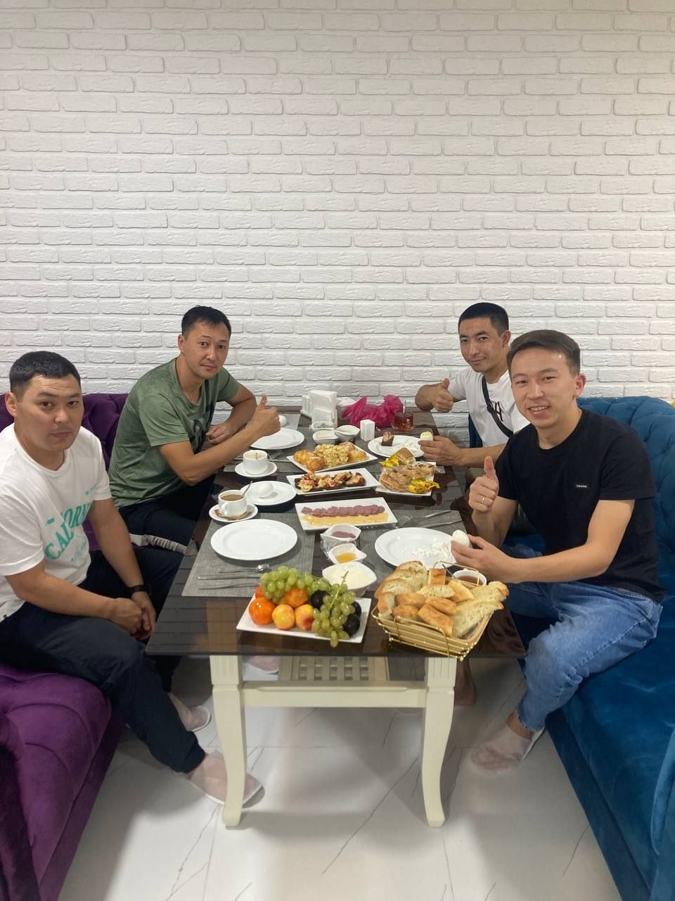 A group of people seated around a table with various food items and drinks.