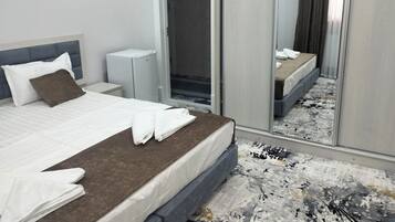A hotel room with a bed, a bedside table, a wardrobe, and a mirror.
