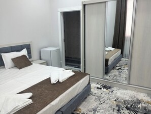A hotel room with a bed, a bedside table, a wardrobe, and a mirror. - Zehra Hotel (Bukhara)