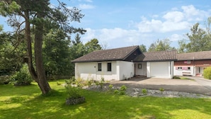 A two-story house with a tiled roof, a garage, and a well-maintained lawn. - Vacation home with parking lot Pet-friendly in the ski area (Wildhaus-Alt Sankt Johann)