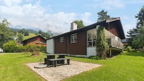 A two-story house with a patio area featuring a table and benches. - Vacation home with parking lot Pet-friendly in the ski area (Wildhaus-Alt Sankt Johann)