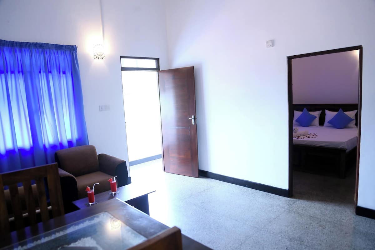 A hotel room with a bed, a sofa, a table with drinks, and a view of the outside.