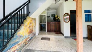 A staircase with a colorful mural, a wooden door, and a small indoor garden area. - Emerald Coast Hotel Negombo (Kochchikade)