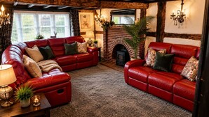 Una sala de estar acogedora con sofás de cuero rojo, una chimenea y un amplio ventanal con persianas.