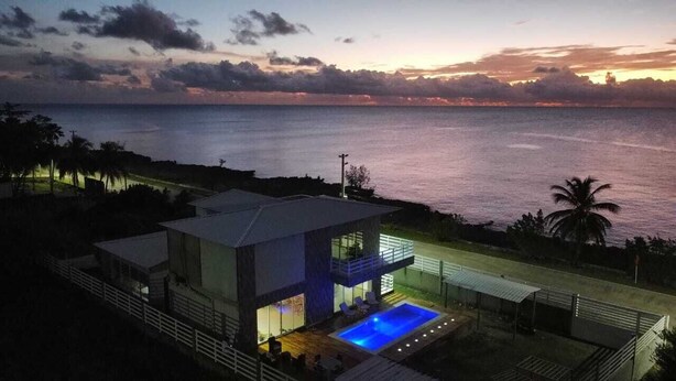 A modern house with a pool, overlooking a body of water at sunset. - STEPHENS HOUSE, 7 color ocean front San Andres Islands. (San Andrés y Providencia)