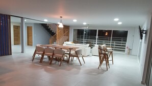 A spacious living area with a dining table and chairs, a sofa set, a staircase, and large windows. - STEPHENS HOUSE, 7 color ocean front San Andres Islands. (San Andrés y Providencia)