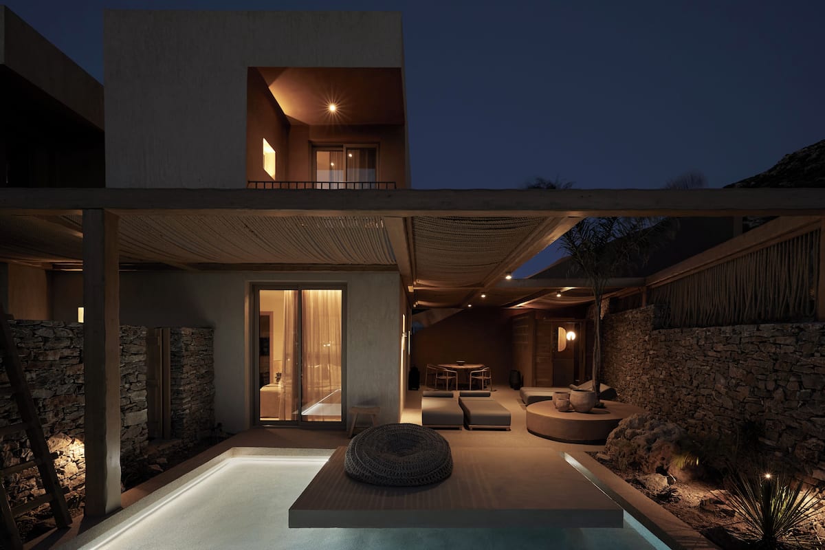 Una casa moderna con piscina, paredes de piedra y un balcón.