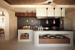A modern kitchen with a curved island, pendant lighting, and built-in storage. - ADĀMA - A Signature Collection by Zálo Spaces (Adults Only) (Faistos)