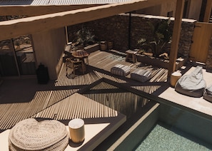A sunlit outdoor seating area with a pool, stone walls, and a wooden pergola. - ADĀMA - A Signature Collection by Zálo Spaces (Adults Only) (Faistos)