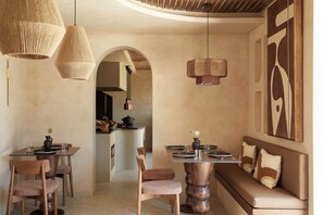 A modern dining area with a wooden table, chairs, and a bench. There are hanging wicker lights and a wall-mounted light fixture. - ADĀMA - A Signature Collection by Zálo Spaces (Adults Only) (Faistos)