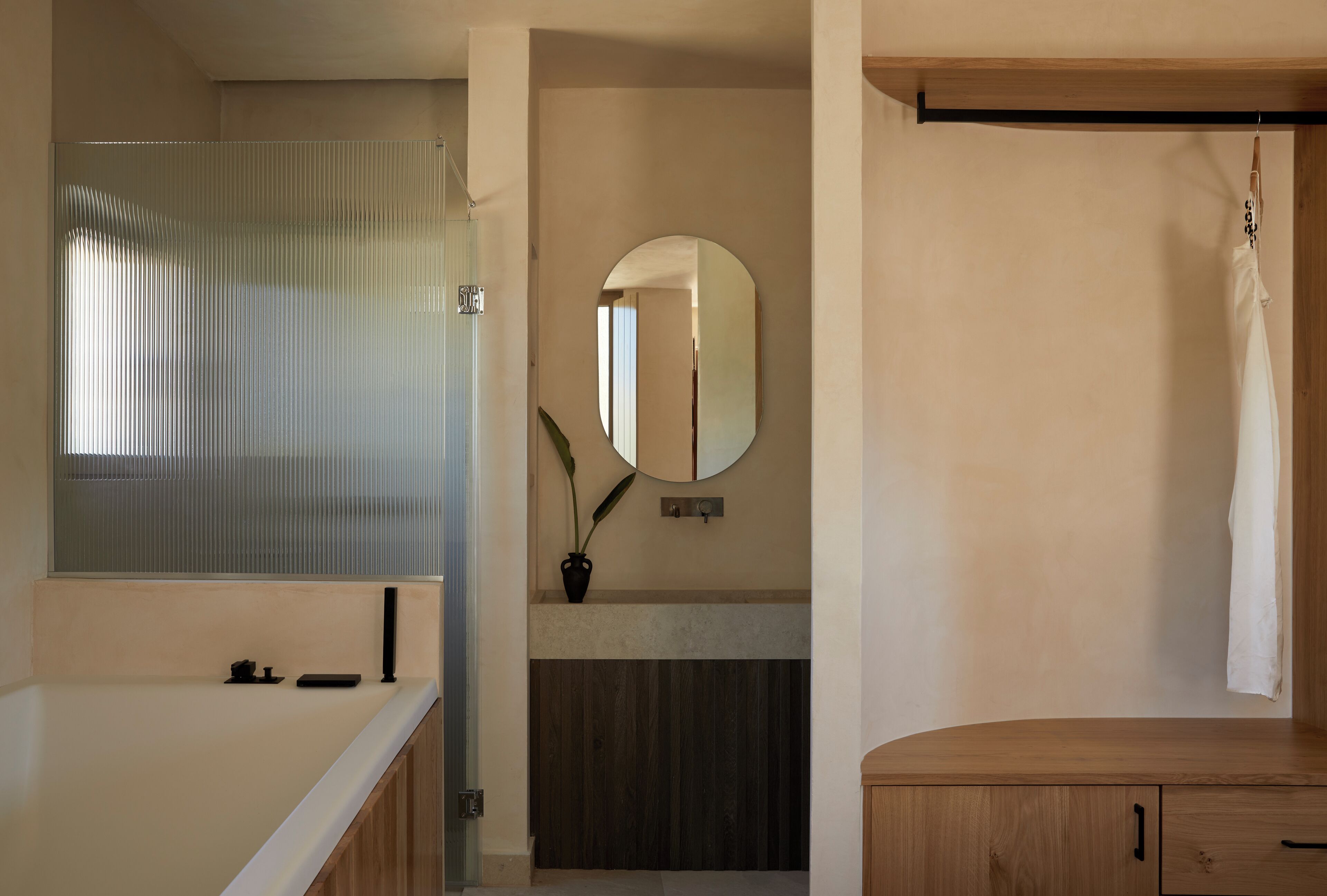 A bathroom with a glass shower enclosure, a wooden vanity with a mirror, and a towel hanging on a rack.