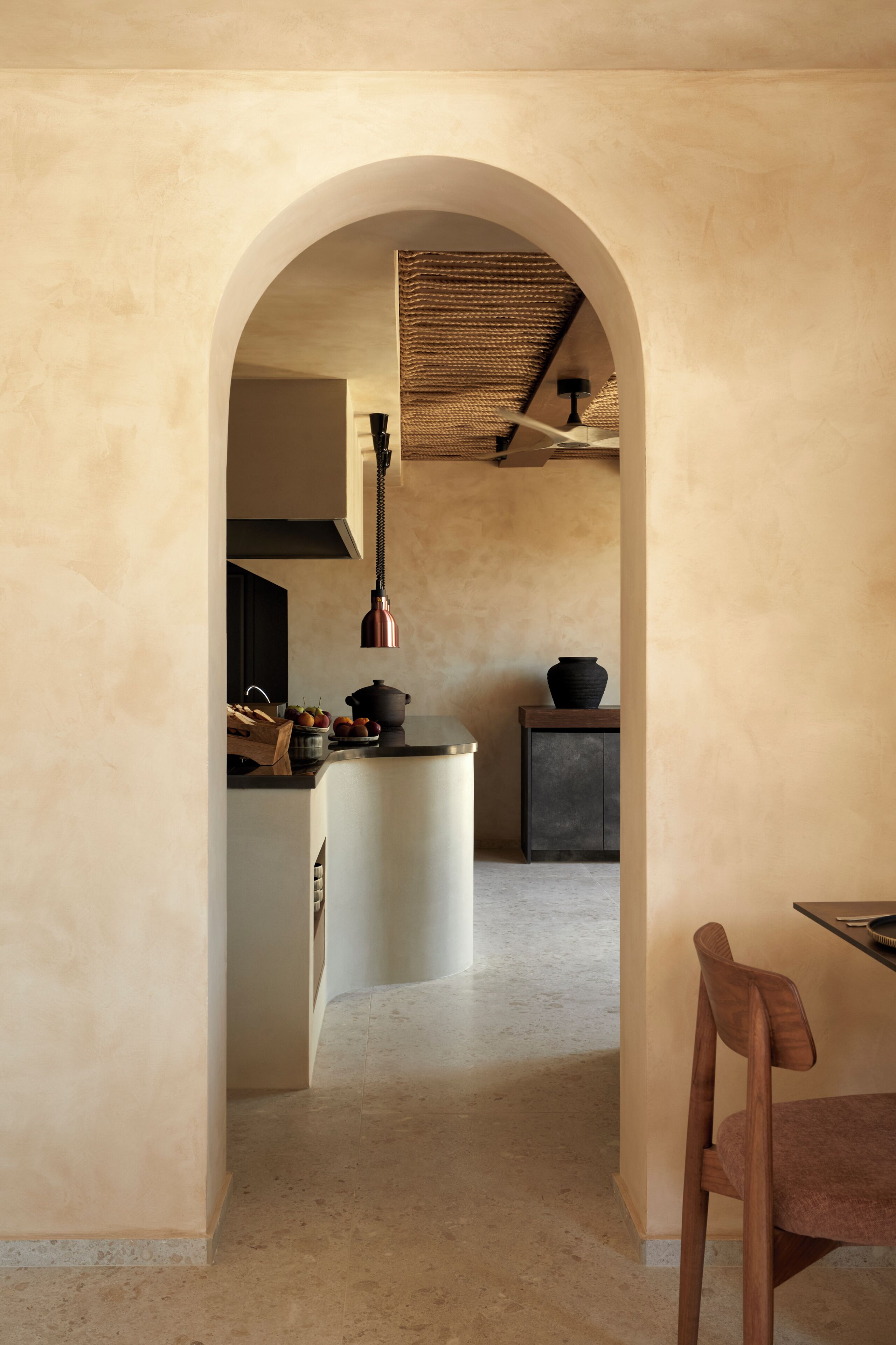 A kitchen with a central island, a hanging light fixture, and a wooden chair.