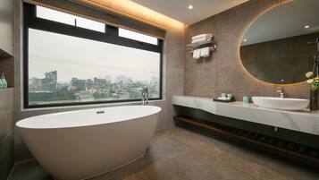 Een moderne badkamer met een vrijstaand bad, een groot raam en uitzicht op de stad.