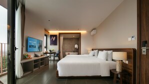 Una habitación de hotel moderna con una cama grande, un escritorio, un televisor y un balcón.