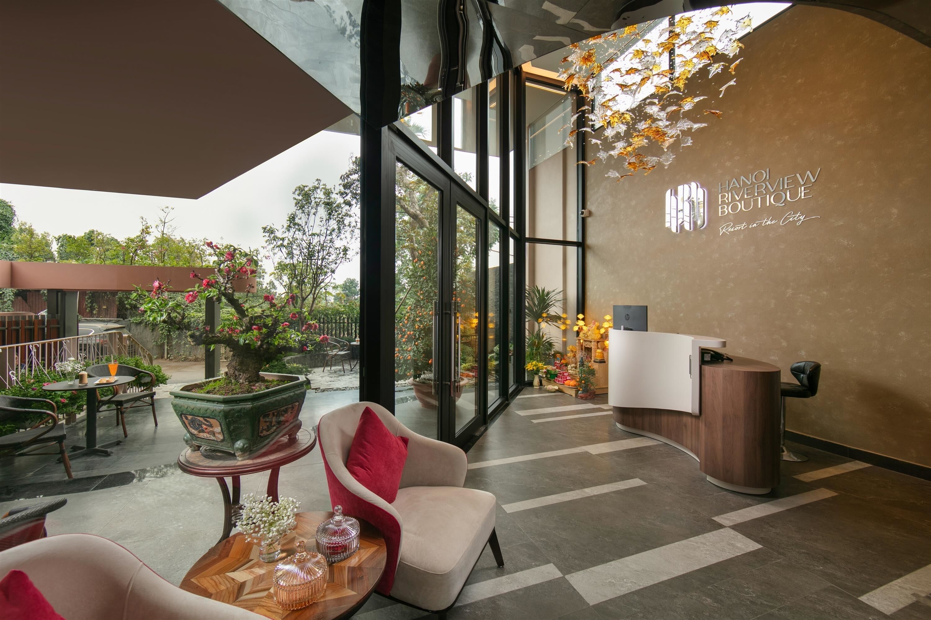 A modern interior with a reception desk, seating area, and large windows overlooking a garden.
