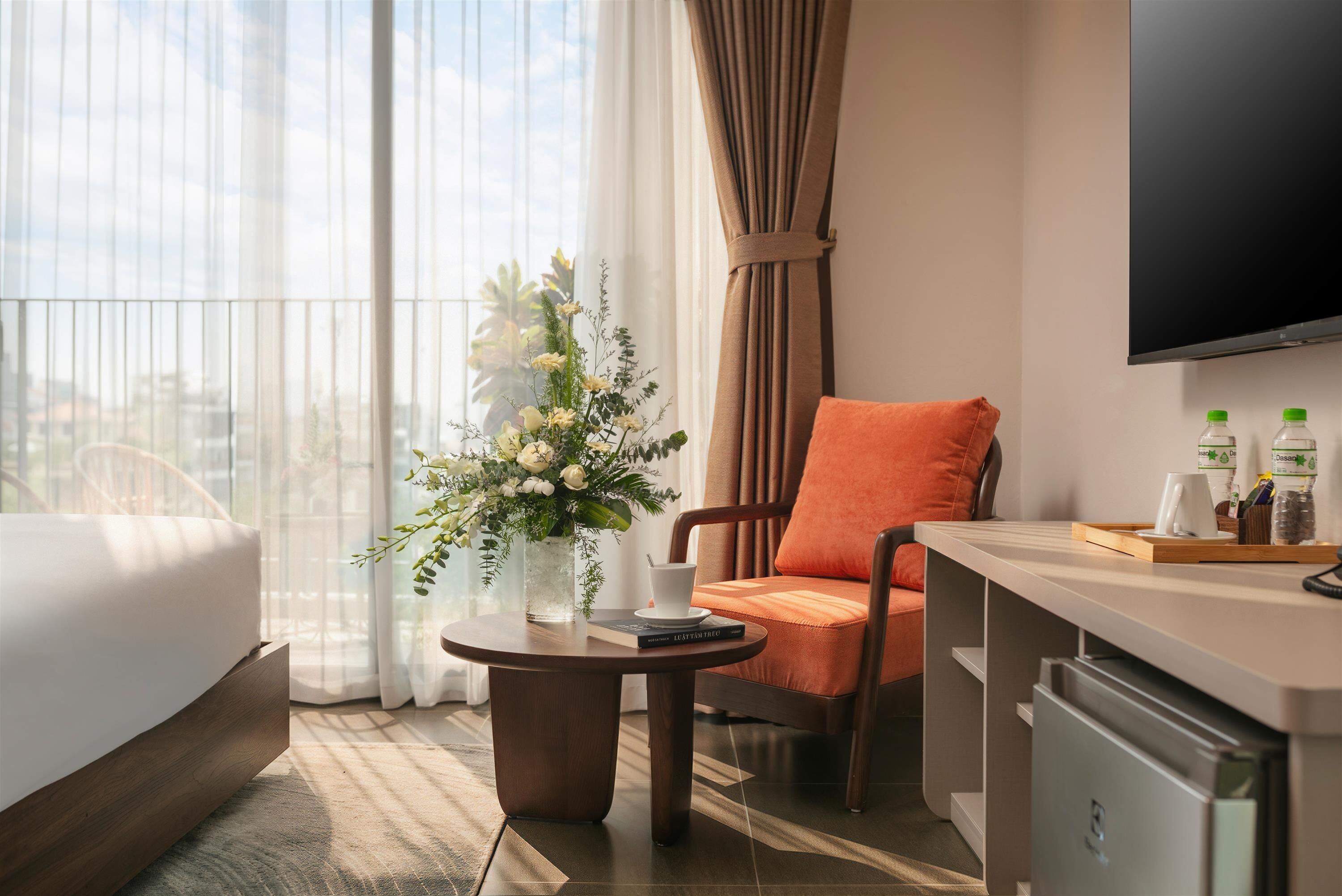 A hotel room with a bed, a desk, a chair, a TV, and a window with curtains.