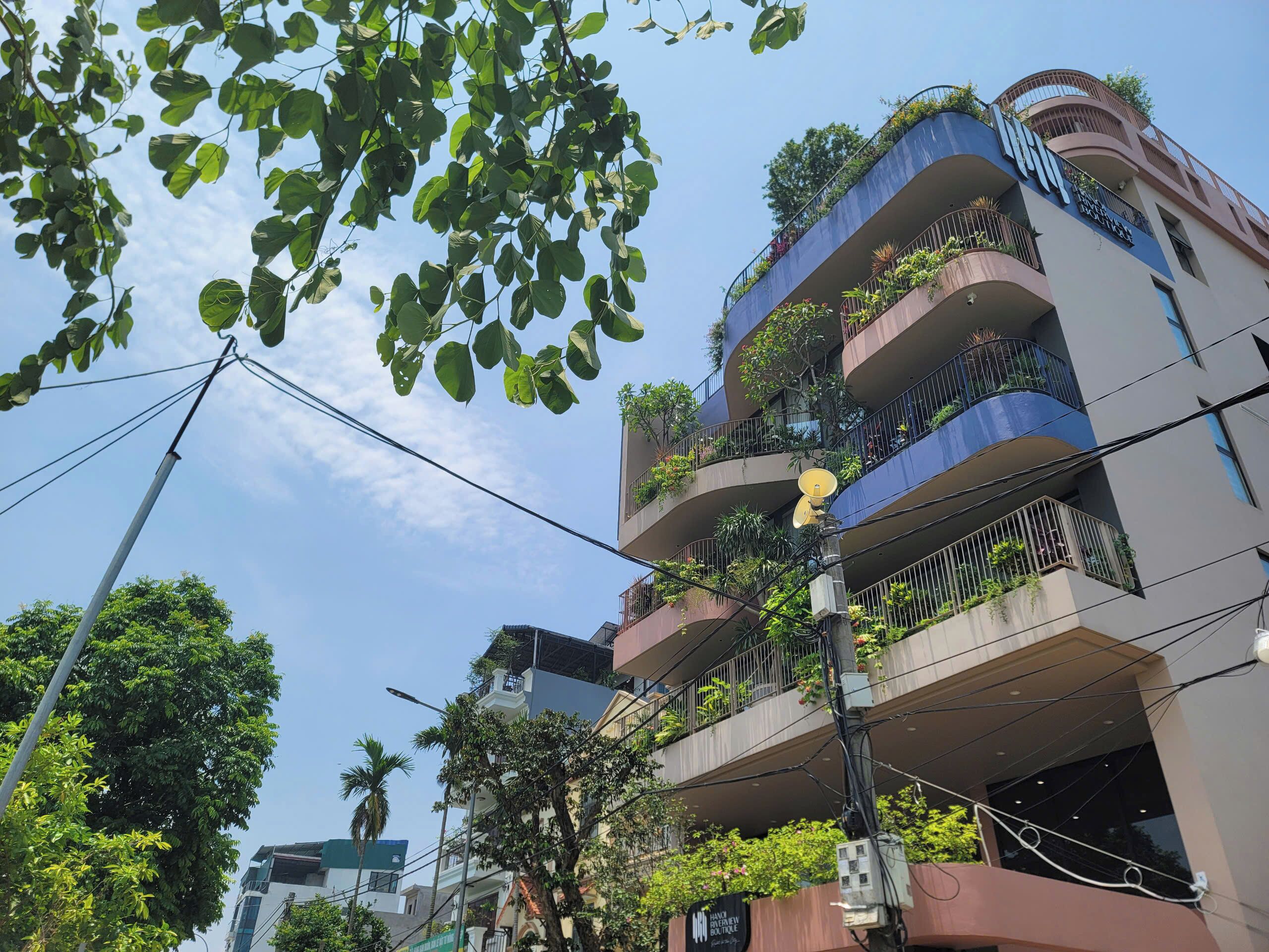 A multi-story building with balconies, some with plants.