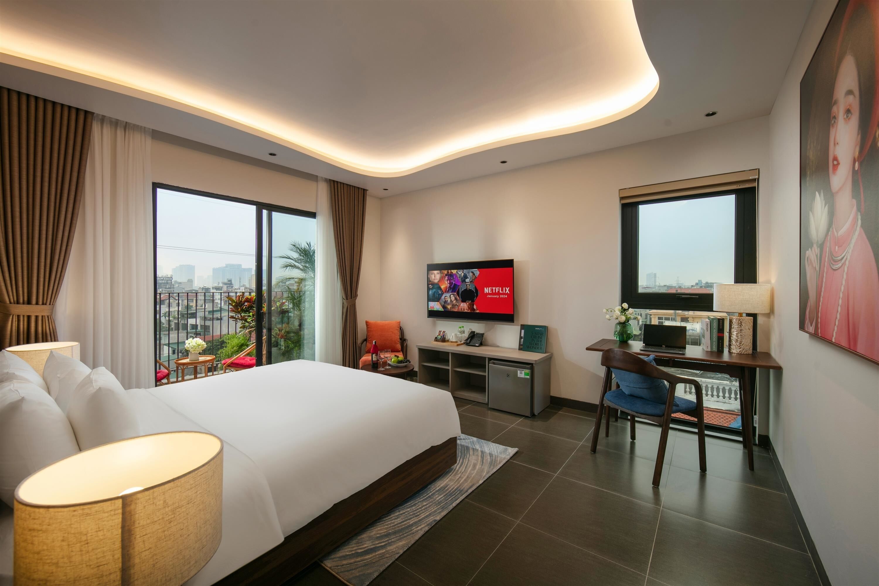 Una habitación de hotel moderna con una cama grande, un escritorio con televisor y vistas a la ciudad.