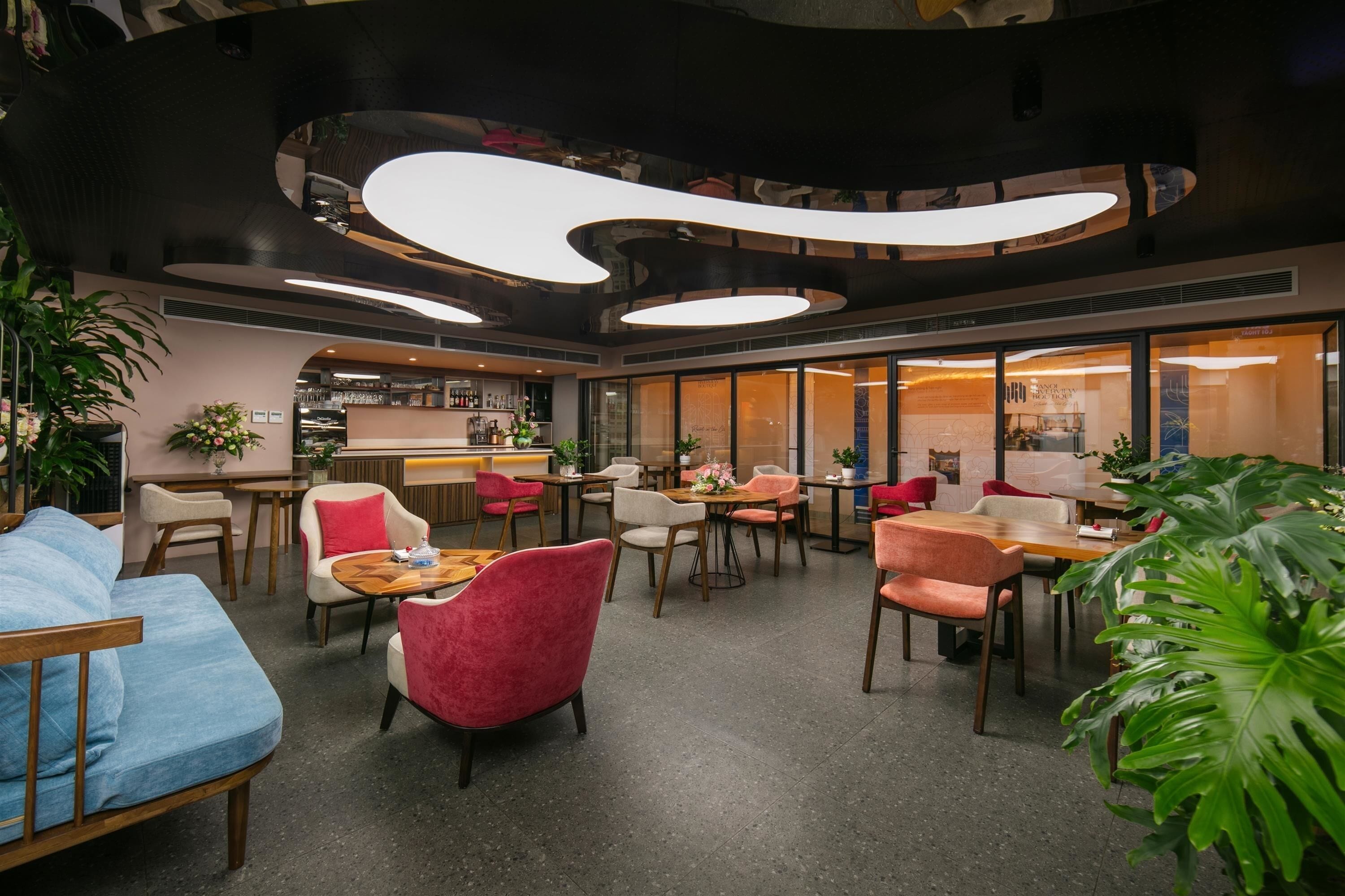 Un hall d’hôtel moderne comprenant un bar, des espaces de détente et un comptoir d’accueil.