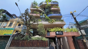 Un edificio de varios pisos con balcones, algunos con plantas. Escaleras conducen a la entrada.