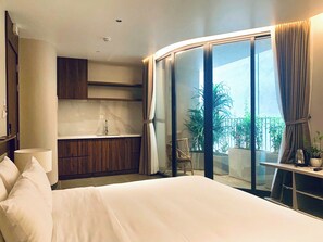 Een moderne hotelkamer met een bed, een badkamer met een wastafel en een balkon met planten.