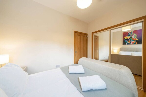 A hotel room with a bed, a sofa, a mirror, and a painting on the wall. - Church House - Montrose Getaway (Montrose)