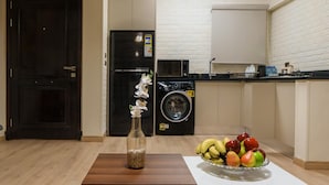 Una cocina con refrigerador, lavadora y un frutero sobre la encimera.