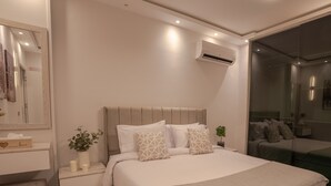 Un dormitorio moderno con una cama grande, mesitas de noche, un espejo y un equipo de aire acondicionado.