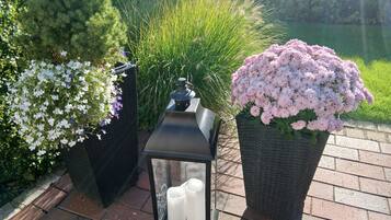 Een tuin met een lantaarn, kaarsen en bloempotten.