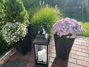 A garden setting with a lantern, candles, and potted flowers. - Apartment 'Ferienwohnung Schwalbennest' with Wi-Fi (Niebüll)