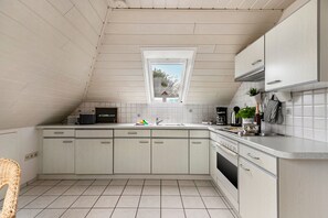 Una cocina compacta con techo inclinado, una ventana y horno empotrado.