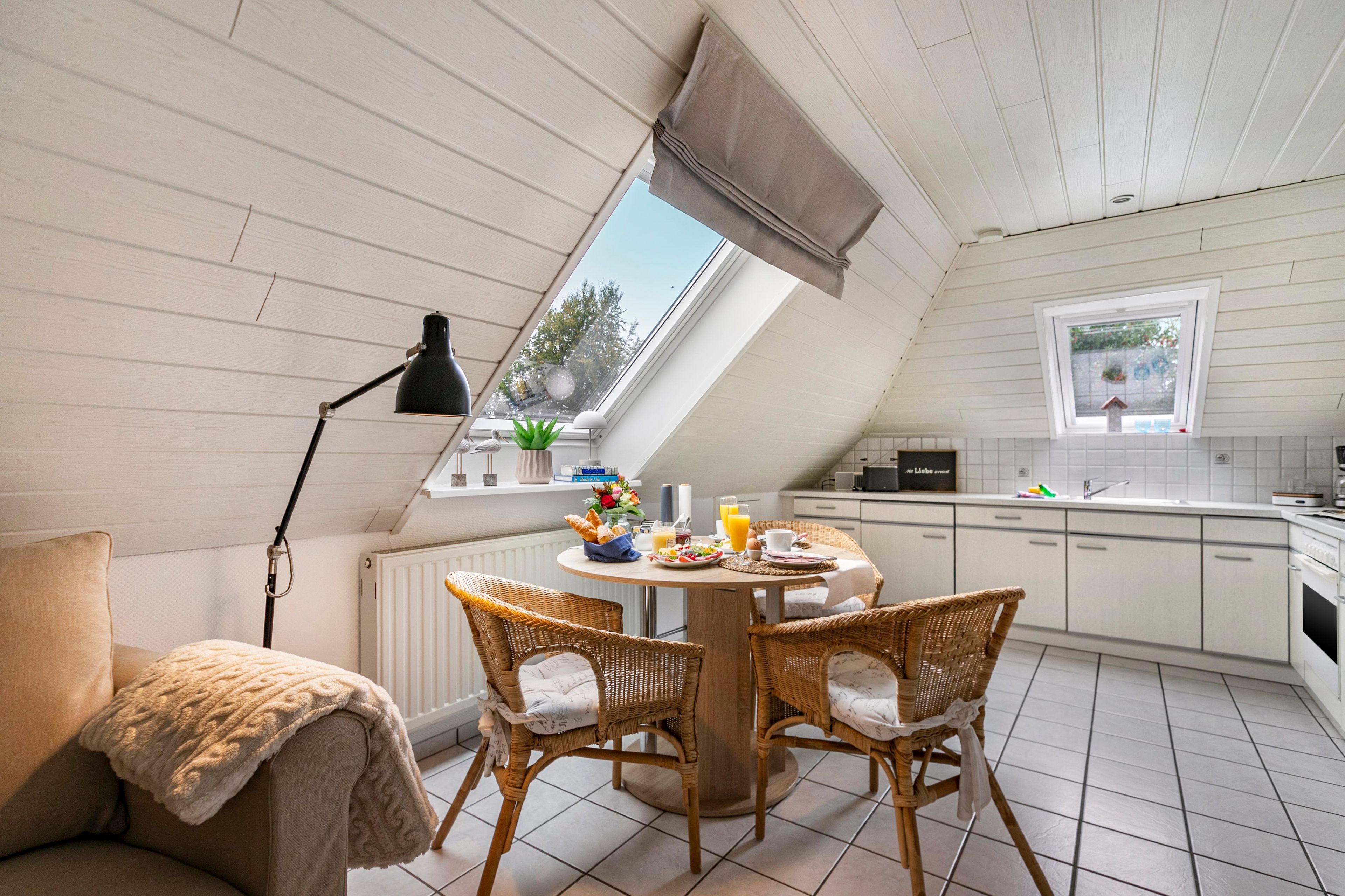 A dining area with a table, chairs, and a window overlooking a garden.
