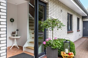 Une maison moderne avec un escalier, une petite table avec une lampe et un pot de fleurs.