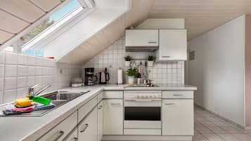 A modern kitchen with a built-in oven, a coffee maker, and a kettle.