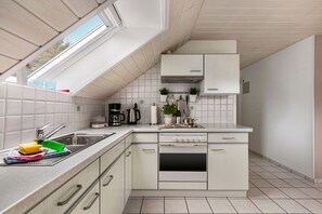 A modern kitchen with a built-in oven, a coffee maker, and a kettle.