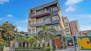 A multi-story hotel with balconies, a gated entrance, and a well-maintained garden. - Hotel Royal City (Noida)