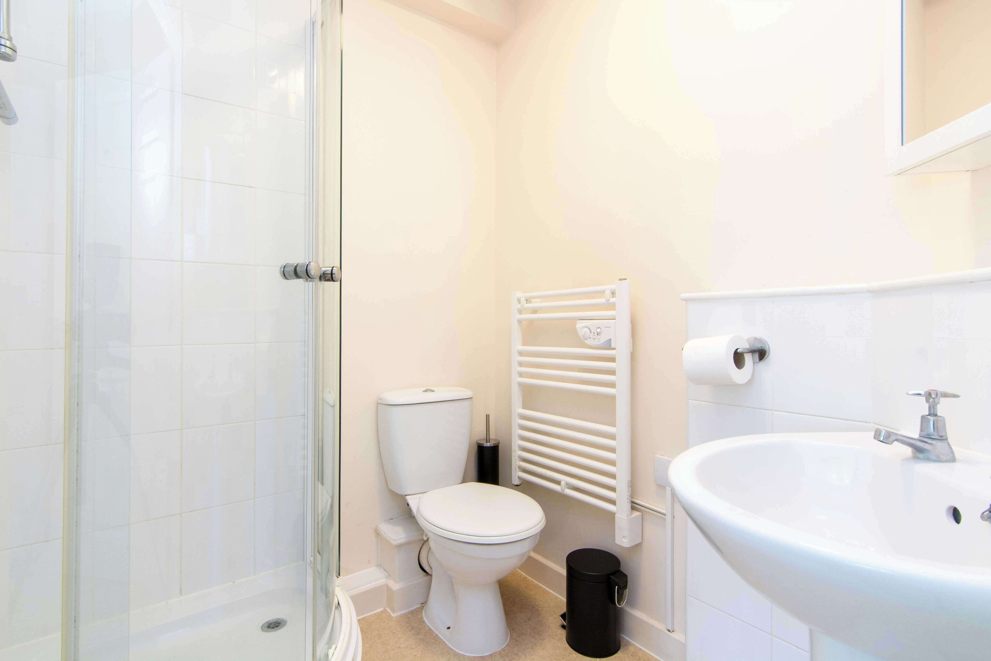 A small, modern bathroom with a toilet, a sink, and a glass shower enclosure.